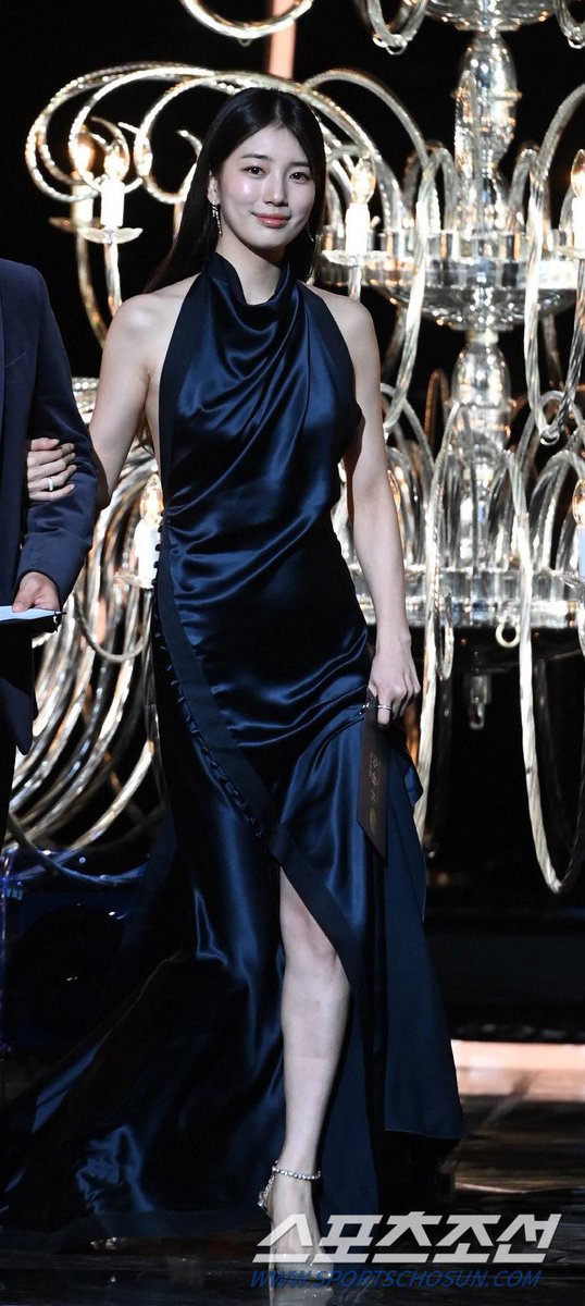 kwaveone's tweet photo. Bae Suzy shone at the #BlueDragonFilmAwards2023, captivating attention with her fashion choice. She selected a form-fitting, satin dress in a deep blue-black shade by #DanielleFrankel, featuring a stunningly draped design. Her elegant attire set her apart on stage from other actresses.

#BAESUZY #SUZY #배수지 #수지