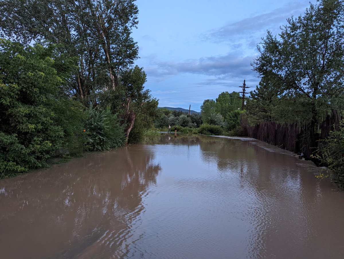 NMDOT's tweet photo. N.M. 240 outside of Taos. The road is closed due to flooding after very heavy rains–water is almost 4 feet deep in some spots of the road. Photography by the Joseph Mondragon, Supervisor for the Taos Patrol. #TurnAroundDon'tDrown #DistrictFive https://t.co/ayUthMRLCz