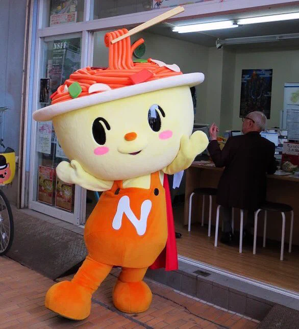 Yakisupa-man, a smiling superhero whose fried spaghetti brains are being eaten, is the mascot of Nogata City, Japan. 