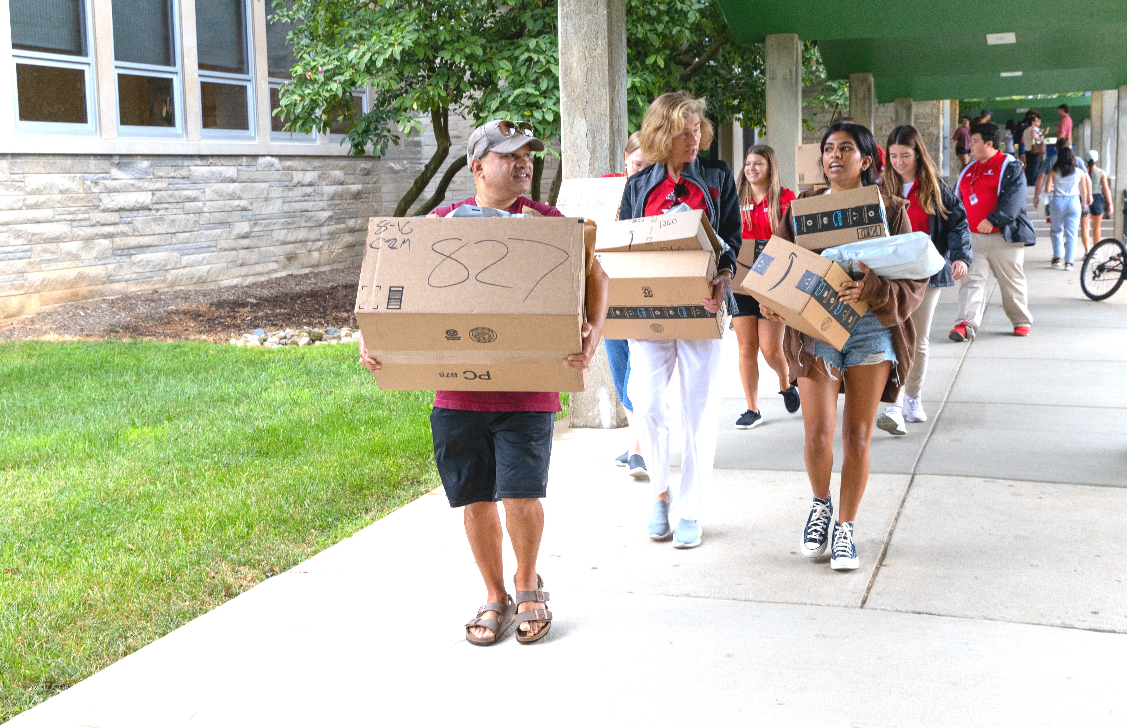 President Whitten helps a first-year student carry boxes through McNutt courtyard to her new dorm room.