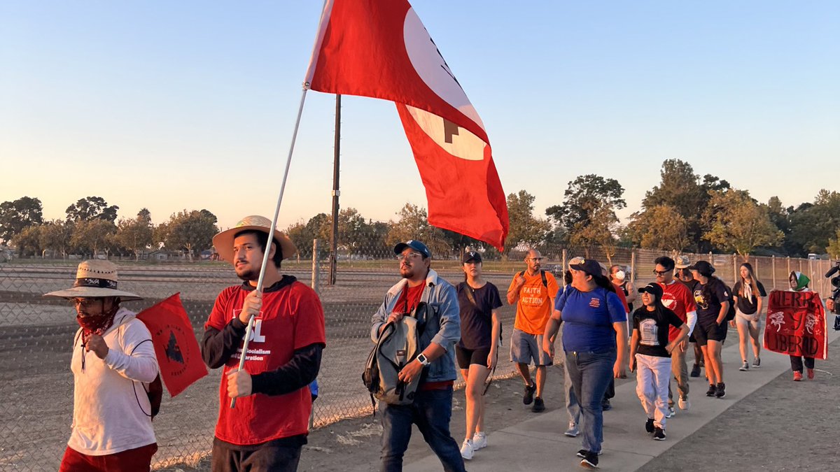 Peaceful marchers with a UFW flag, walking in the sunrise.