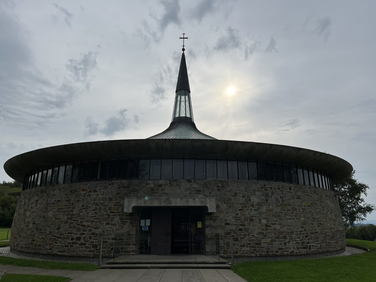 DunleavyBernard's tweet photo. The fifth stop on our tour of Liam McCormick’s #MagnificentSeven Donegal churches. St Aengus at Burt - extraordinary echoing of An Grianán of Aileach in its shape, oculus altar light, Oisín Kelly reliefs, Imogen Stuart cross. #LiamMcCormick #RHA @RHAGallery @govisitdonegal https://t.co/6ErPDEDjvj