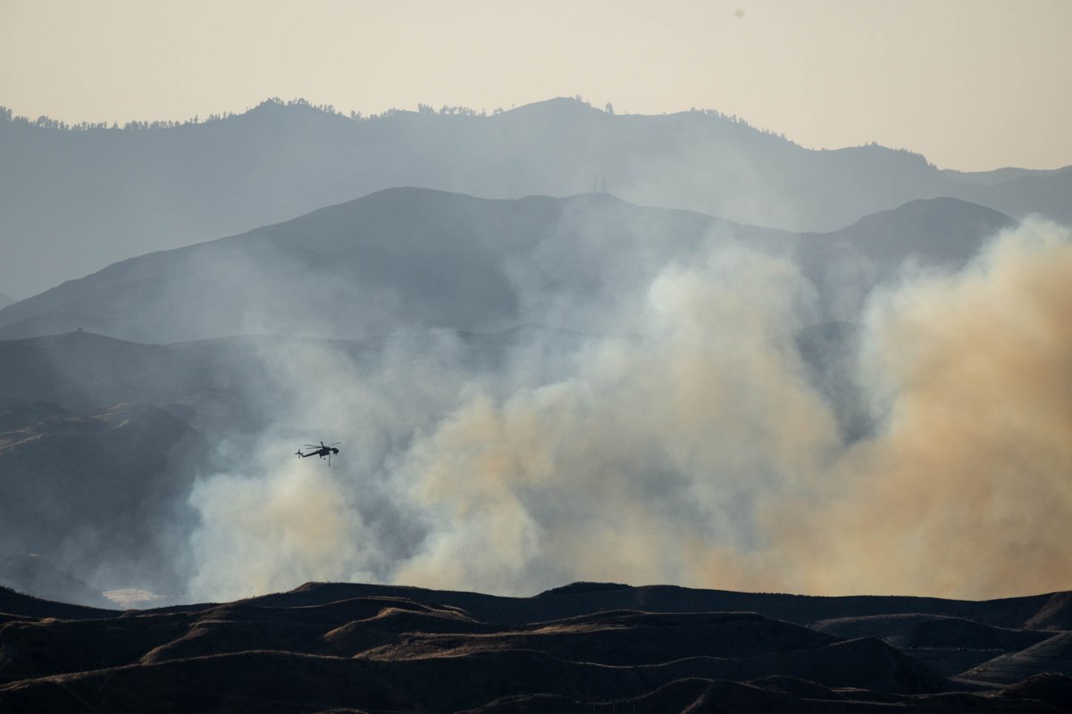 vidcrane's tweet photo. A water-dropping helicopter moves in to make a drop on a 50-acre brush fire called the #Quailfire that broke out around 5:30 near the I-5 freeway and Lake Hughes road Wednesday, August 17, 2022. #brushfire #LACOfire https://t.co/7lyHzUfgys