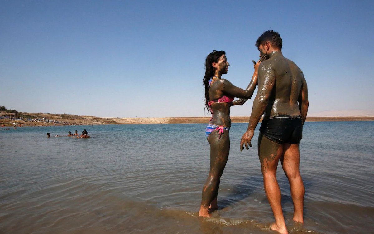 A couple cover themselves in natural mud at the Dead Sea near the West Bank city of Jericho CREDIT: HAZEM BADER/Getty