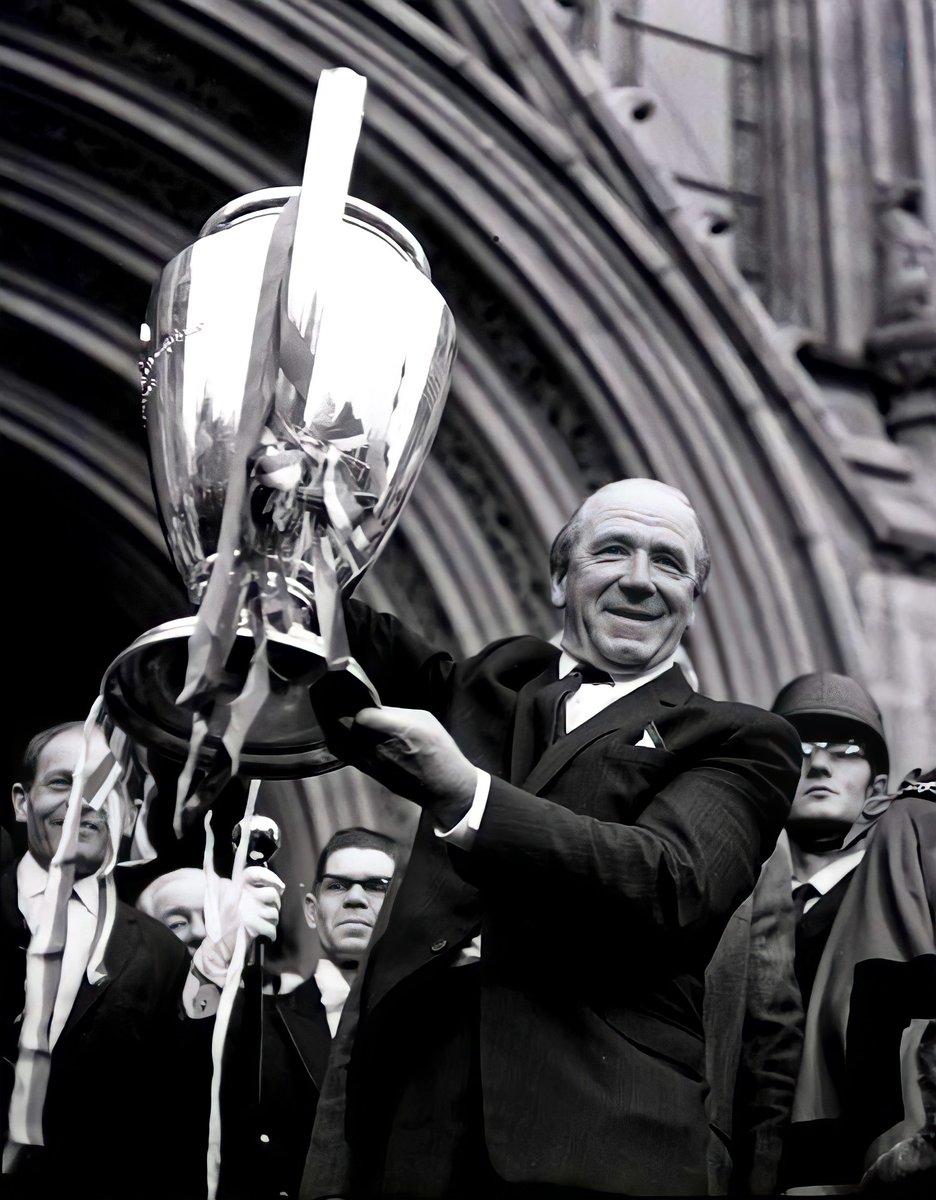A proud Sir Matt Busby raises the European Cup high outside Manchester Town Hall, 1968.