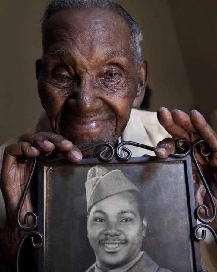 FreeBlckThought's tweet photo. Lawrence Brooks photographed in 2020, holding a photo of himself. 110 years old at the time, he was the oldest living WWII veteran. Born in 1909, he died in January of this year, aged 112. Today—September 12—would have been his 113th birthday. https://t.co/iyXCYguwLB