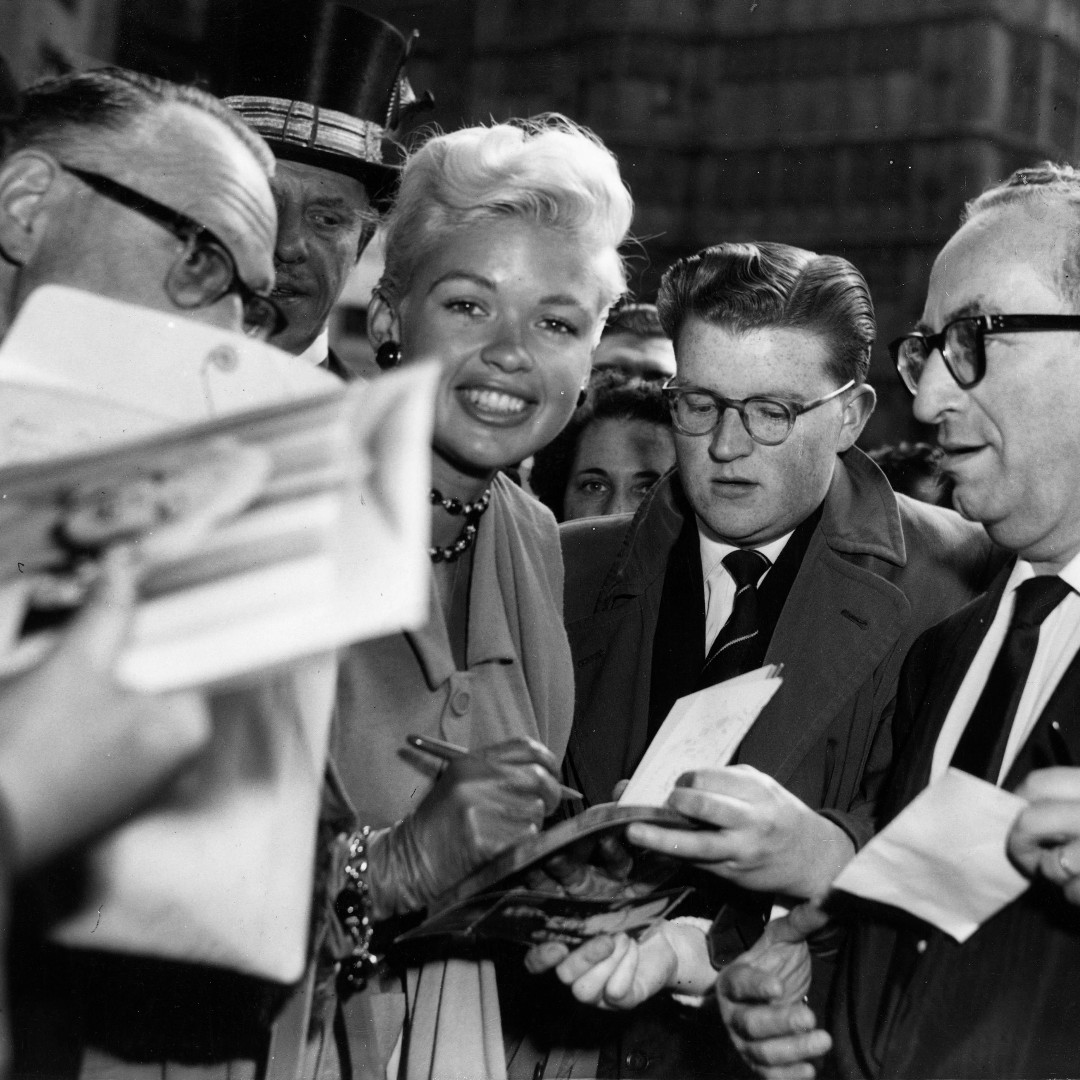 In 1957, actress Jayne Mansfield signs autographs as she arrives at The Dorchester