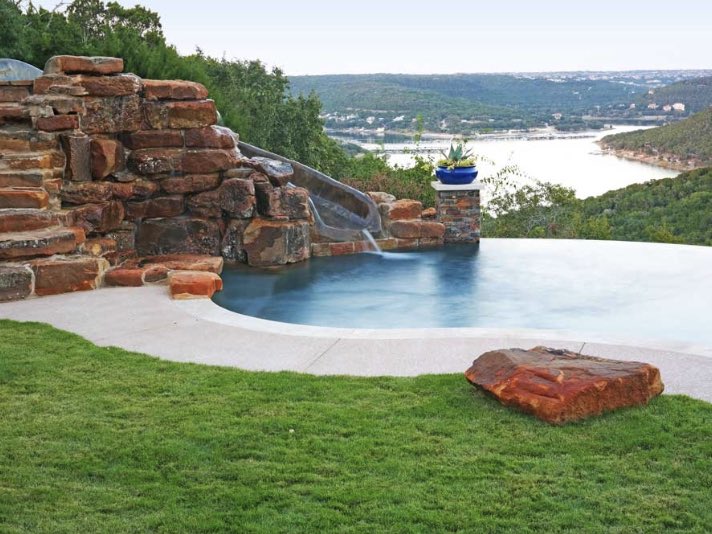 Custom free form pool with a built in water slide is the perfect way to spice up your backyard. #AustinPoolBuilders #AustinSwimmingPools #ReliantPools