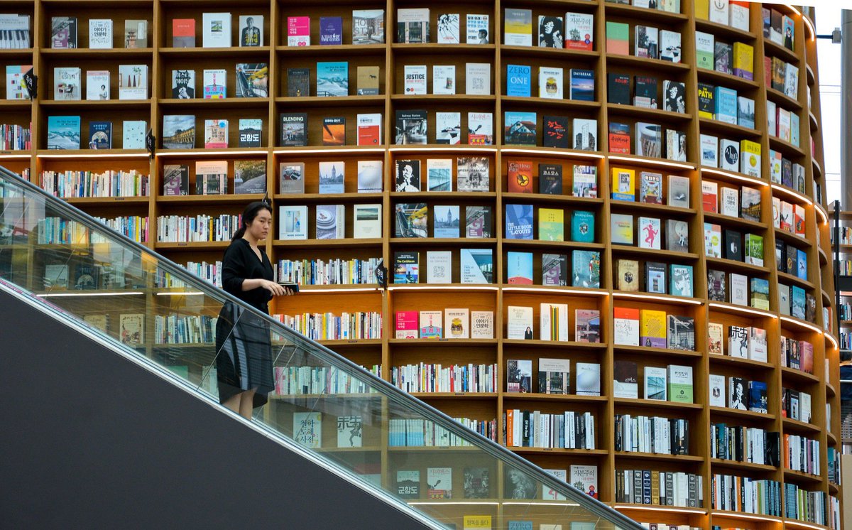 SeoulJournal's tweet photo. "Excuse me, I would like to read that one." She points to the very top shelf.  
Photo by Adli Wahid. #starfieldlibrary #coexmall #southkorea #book https://t.co/K6UaxqDhUT
