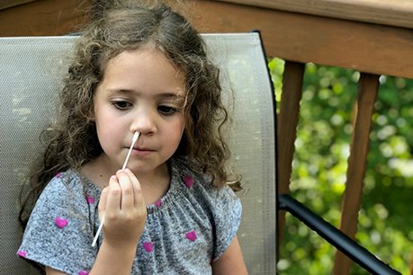 Young child performs self-swabbing for COVID-19 test.
