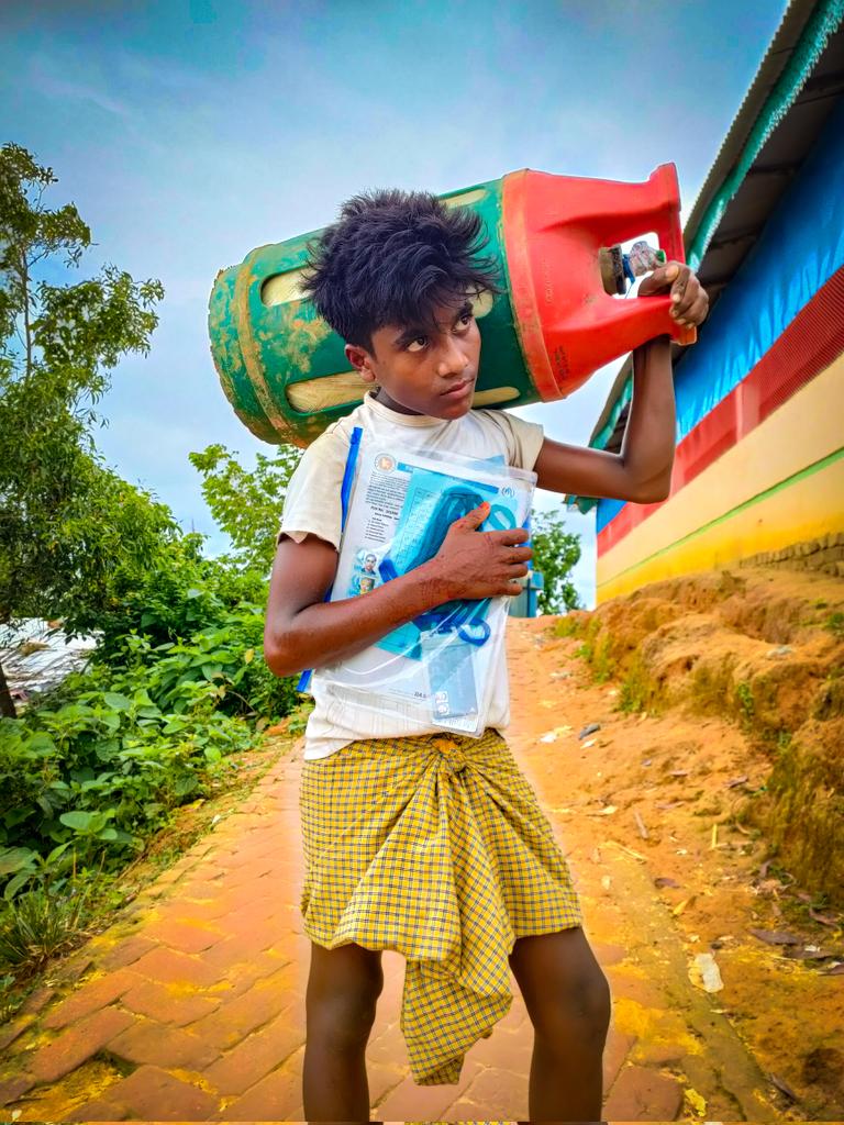 AlomShaker's tweet photo. A #Rohingya boy is carrying gas cylinder from #NGO's distribution point for his family, no one in his family to support such kind of needy things , he is the only boy in his family.
  Rohingya #refugee camp cox's bazaar, bangladesh. 

#Rohingyas #lifematter 
#refugees #Crisis https://t.co/xYeNZoCpdp