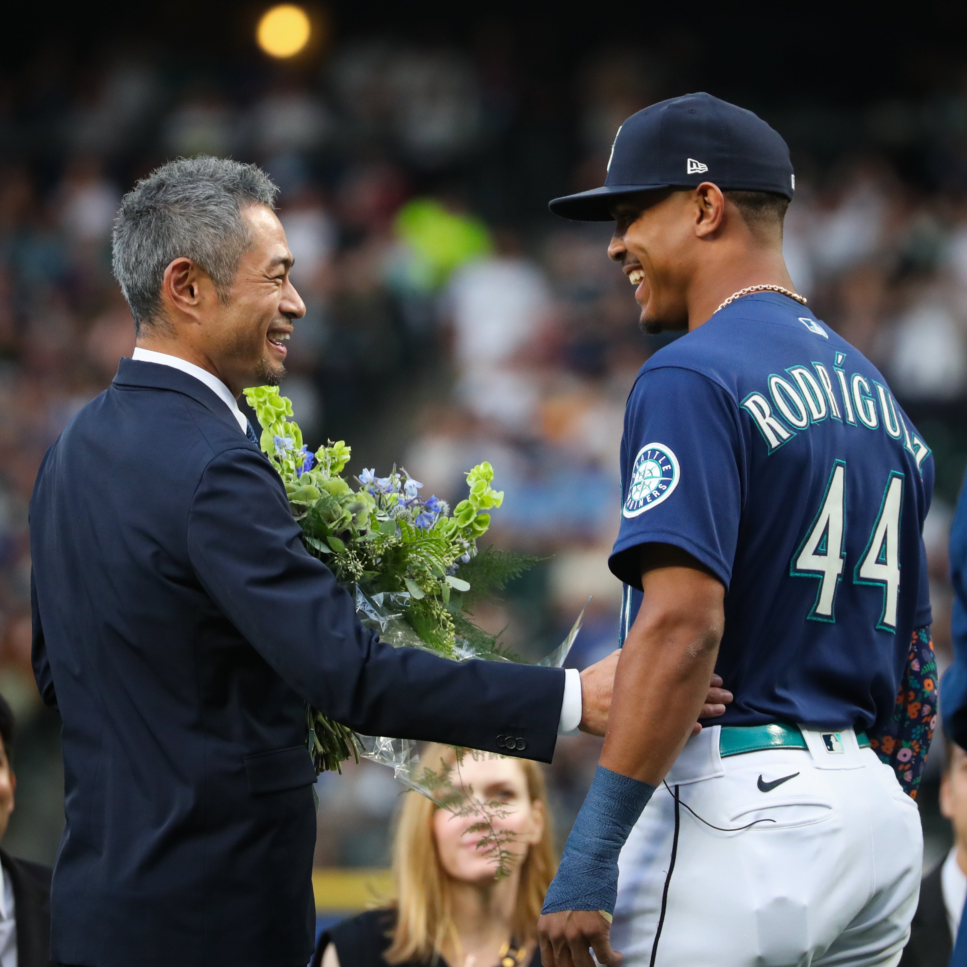 Former Seattle Mariners player Ichiro Suzuki, left, is presented with a  bouquet of flowers by Mariners' Julio Rodriguez as he is inducted into the Mariners  Hall of Fame during a ceremony before