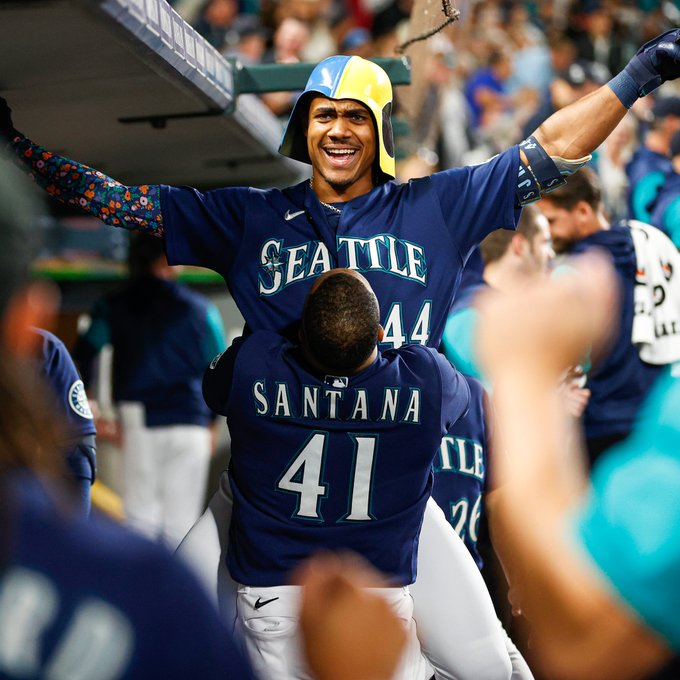 Carlos Santana picks up Julio Rodríguez, wearing the Swelmet, in the dugout after Julio's home run. 