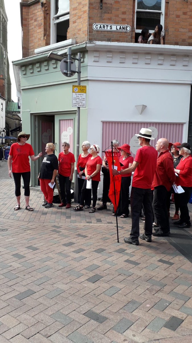 Red Leicester waiting to welcome the giant puppet Storm to Leicester as part of the City Festival. They sang environmental songs to her, including There is no Planet B. Quite an amazing sight.