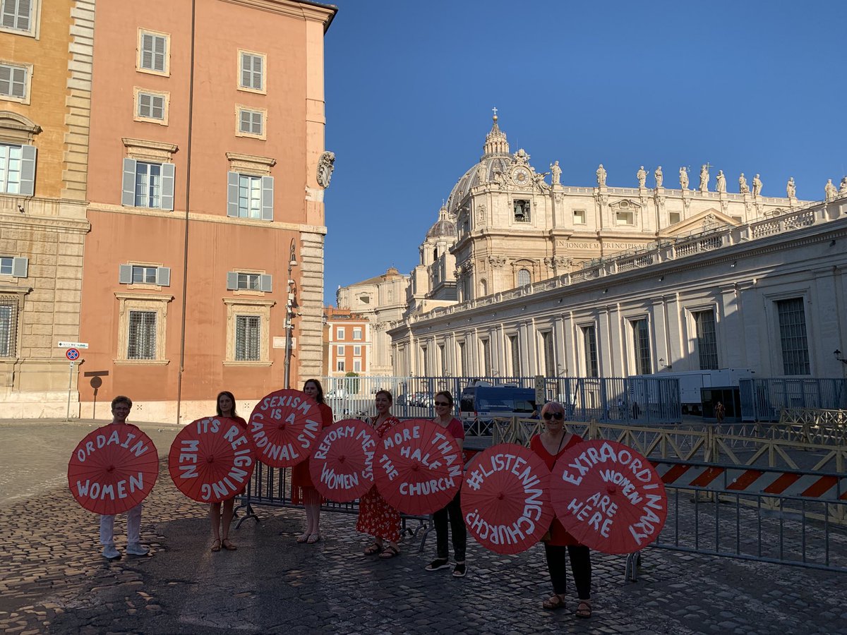 joshjmcelwee's tweet photo. Women’s ordination advocates came outside the hall where Pope Francis is meeting with the world’s Catholic cardinals with messages written on red parasols. The police are now questioning them. (One is my wife, ⁦@dearmisskate⁩) https://t.co/v6tbrr0cN7