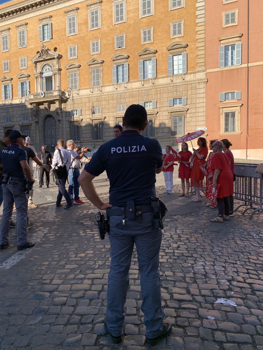 joshjmcelwee's tweet photo. Women’s ordination advocates came outside the hall where Pope Francis is meeting with the world’s Catholic cardinals with messages written on red parasols. The police are now questioning them. (One is my wife, ⁦@dearmisskate⁩) https://t.co/v6tbrr0cN7