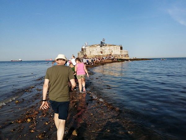 People walking along a shingle path towards St Helen's Fort