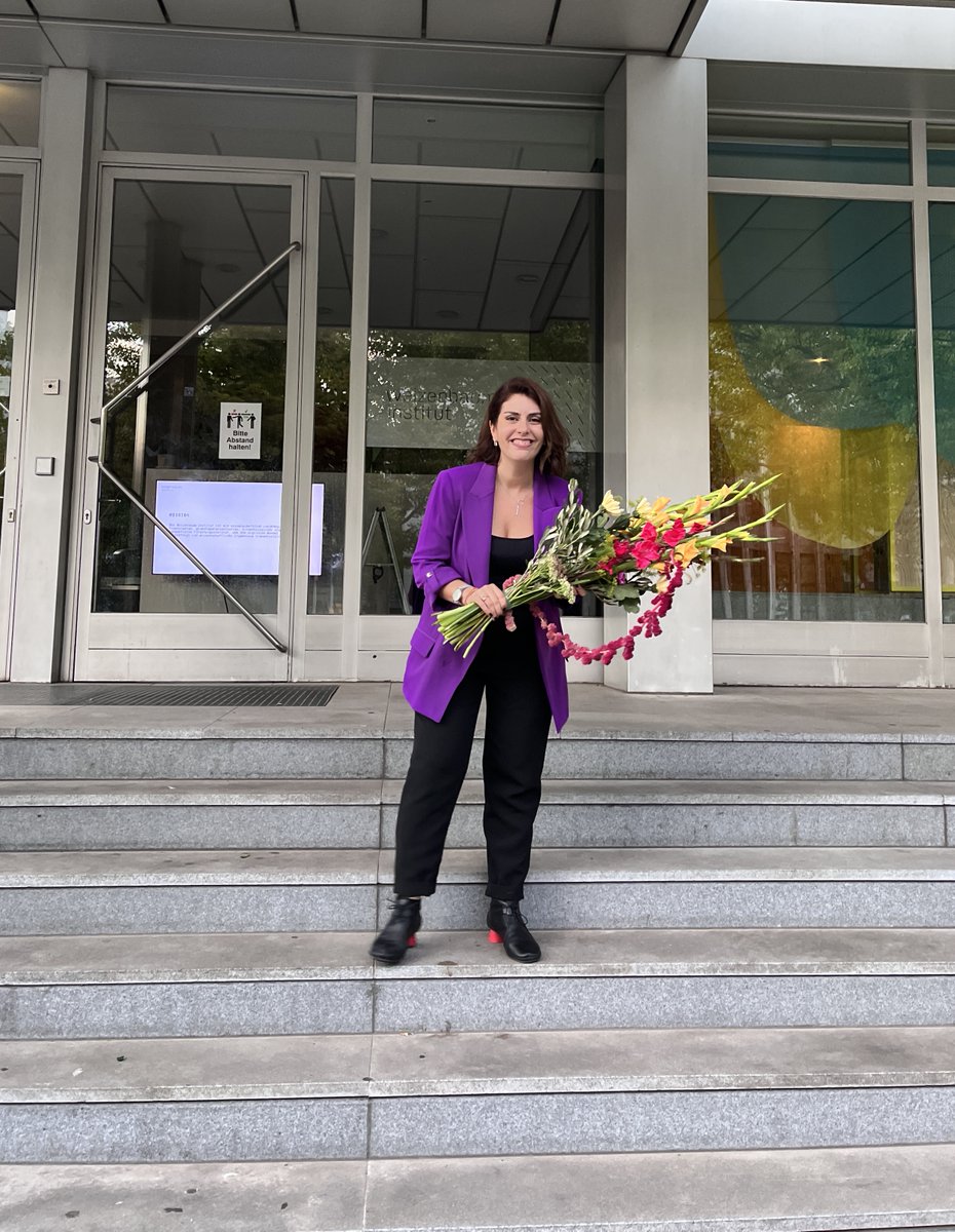 Dr. Milagros Miceli smiling and holding a big bouquet of flowers after successfully defending her dissertation.