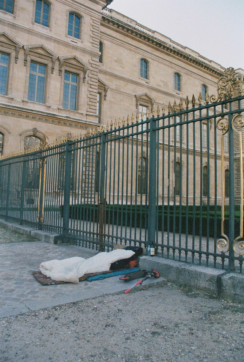 RonniRavid's tweet photo. I got some old film developed and I forgot about this photo I took in Paris. Outside the golden gates of the Louvre rests someone’s make-shift bed. €40b worth of art is in this museum, and outside someone sleeps at it’s steps. The irony really felt overwhelming https://t.co/hOSDK0ntOY