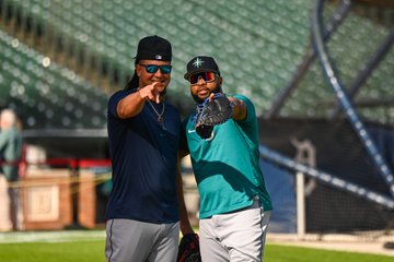 Luis Castillo and Carlos Santana point to the camera during batting practice. 