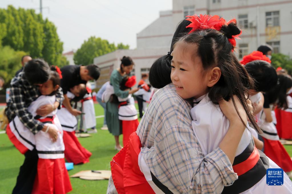 Children wearing hanfu hug their parents at the "Kaibi Ceremony" in