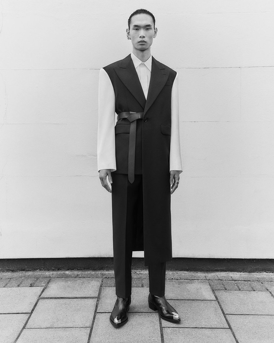 A black tailored jacket with an asymmetric drape and chalk satin contrast sleeves, worn with cigarette trousers and black Punk boots. 

Discover the #McQueenMenAW22 collection: on.alexandermcqueen.com/MensAW22_TW