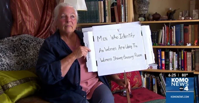 Old woman holding sign "Men who identify as women are using the women's shower/dressing room"