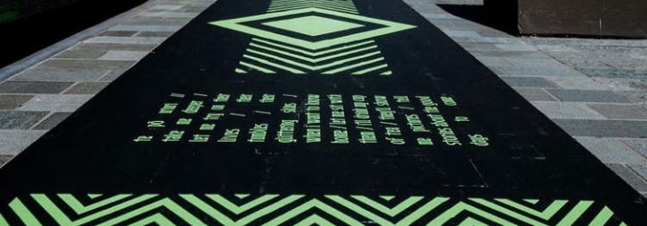 Picture of Te Pō exhibit, green designs on black background on the floor