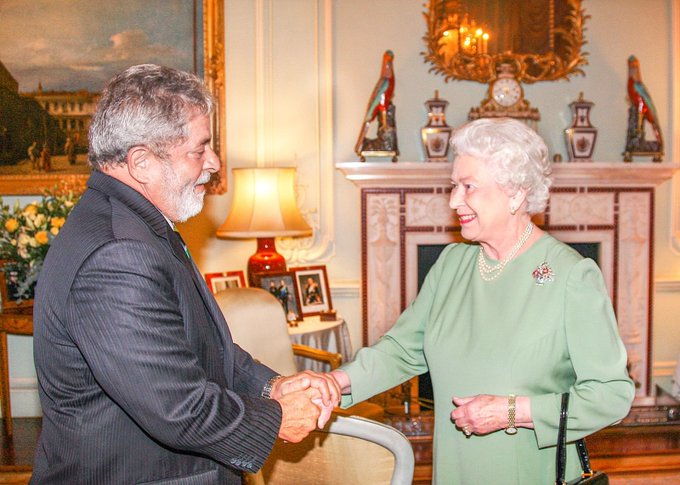 Lula e a rainha Elizabeth II sorriem e apertam as mãos