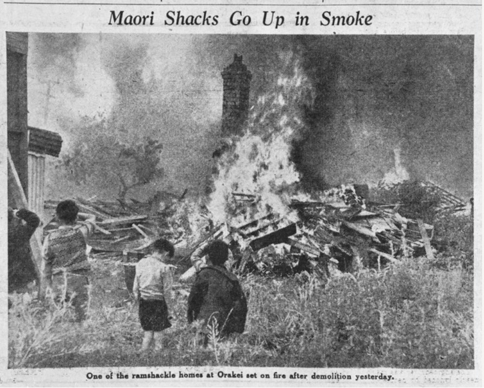 Showing homes of mana whenua of Ngāti Whatua on the Orakei Reserve on fire after being demolished on the instructions of the Commissioner of Crown Lands to make way for the Queen's visit in 1952 -1953 along Tamaki Drive. It took the land under the Public Works Act 1/