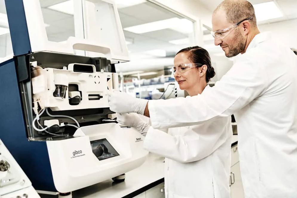 Thermo Fisher Scientific scientists Nektaria Andronikou (left) and Mike Gordon (right) with the CTS Xenon Electroporation System instrument and MultiShot cartridge.