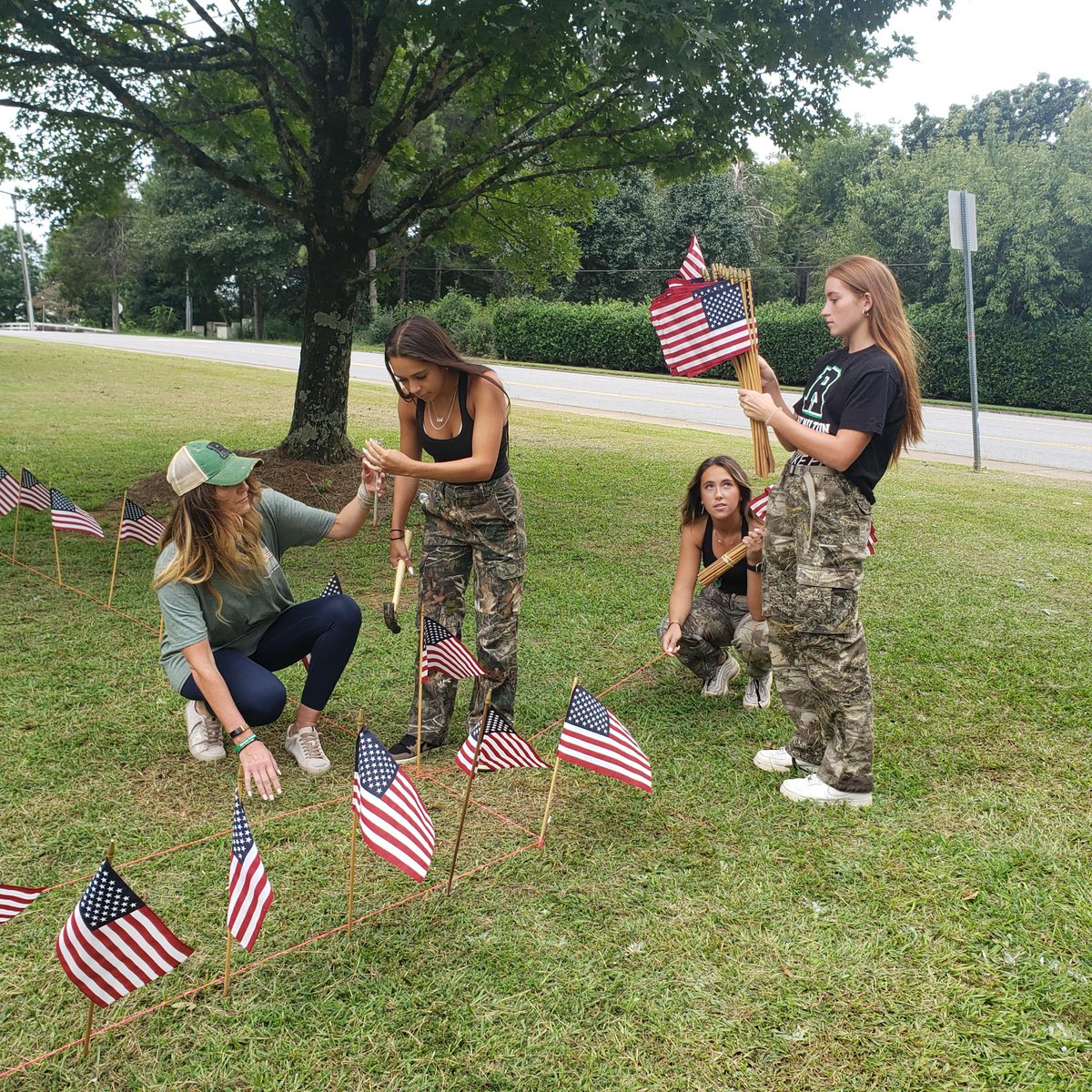 RoswellHighSch's tweet photo. Yesterday members of the class of 2023 and parent volunteers installed 2,996 American flags on the front lawn of RHS. Each flag represents a life lost on September 11, 2001. This is the 13th annual Project 9/11 at RHS. We remember. #project911 #classof2023 #neverforget https://t.co/KjqQQ0scQn