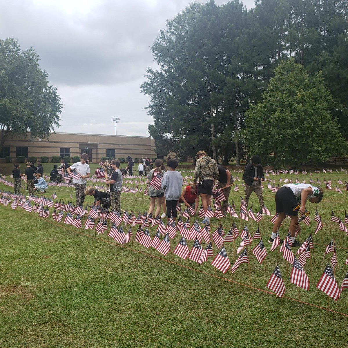 RoswellHighSch's tweet photo. Yesterday members of the class of 2023 and parent volunteers installed 2,996 American flags on the front lawn of RHS. Each flag represents a life lost on September 11, 2001. This is the 13th annual Project 9/11 at RHS. We remember. #project911 #classof2023 #neverforget https://t.co/KjqQQ0scQn