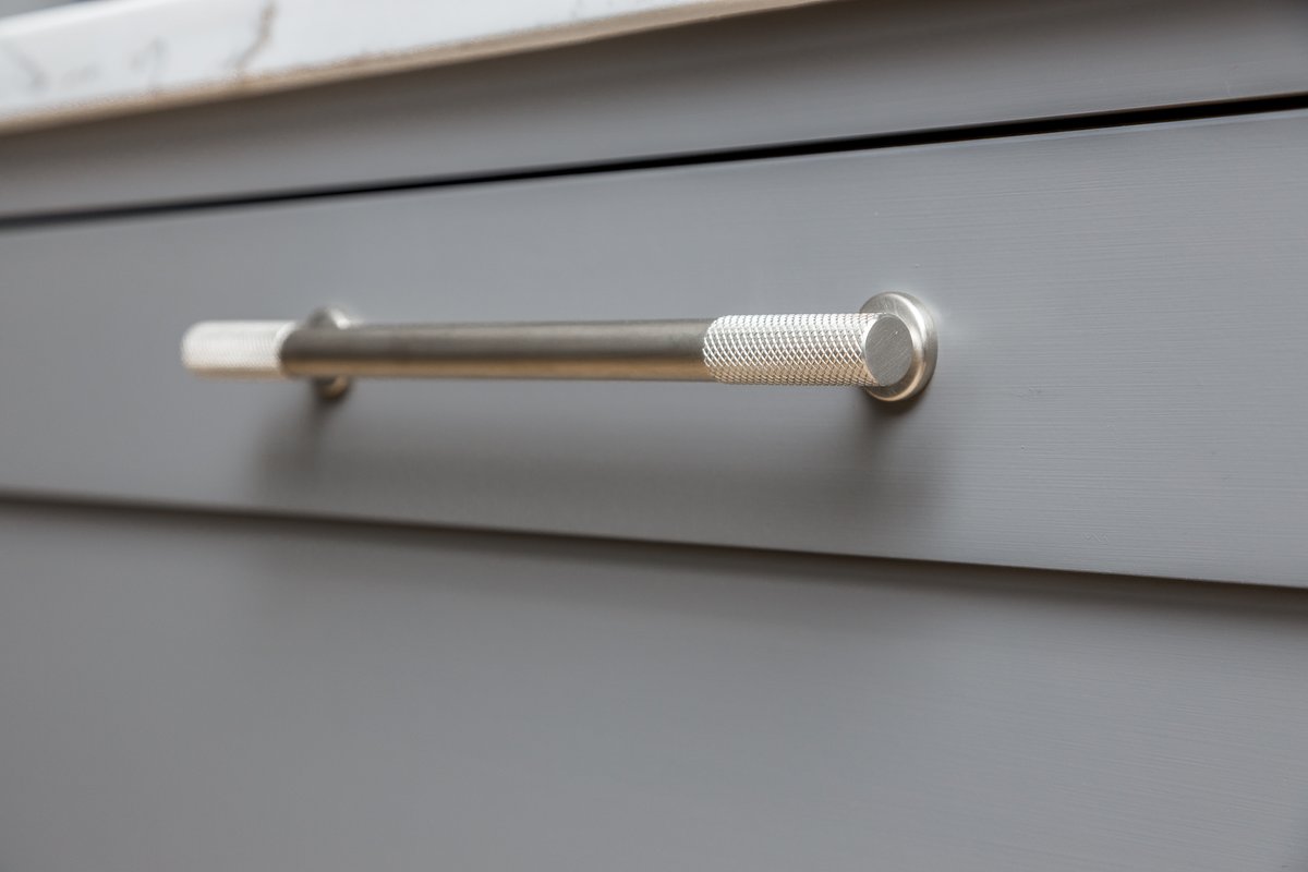 Finishing touches make all the difference to the overall effect of a kitchen. These stylish bar handles with textured ends stand out against the minimalist shaker cabinetry making this a bold and inviting kitchen.