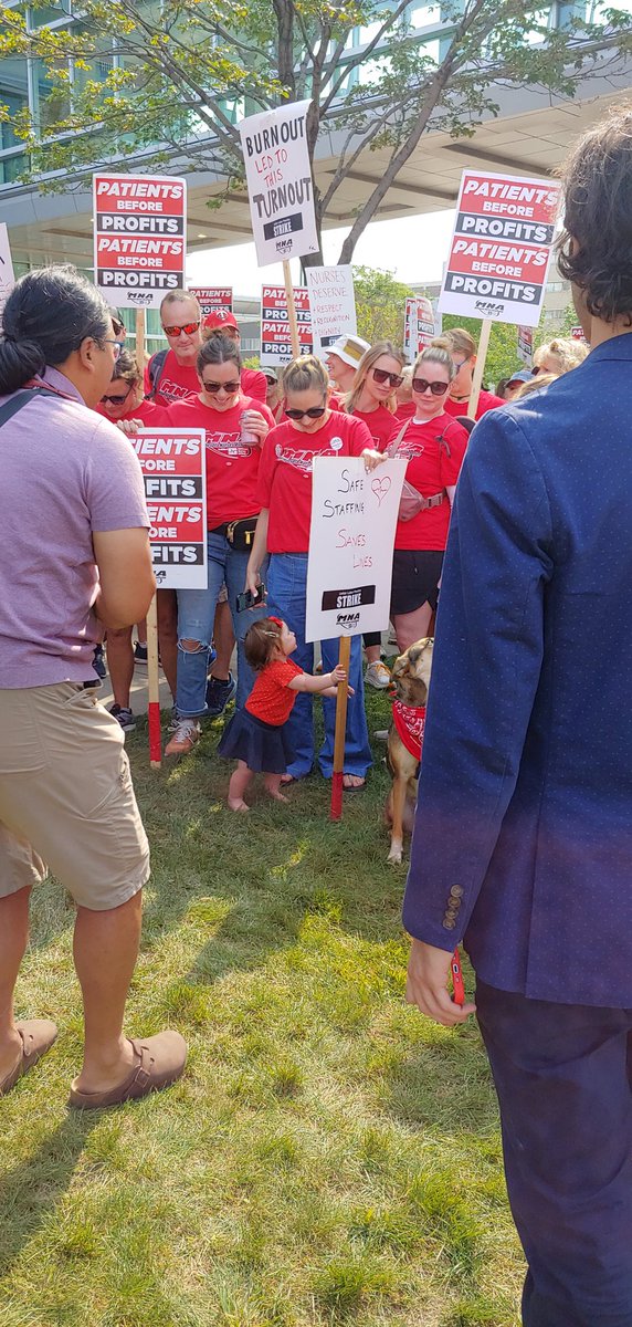 Infant Kaylee pulled herself up by a picket sign at Southdale before her dad Jeff addressed media, saying inadequate hospital staffing is pulling him in to too many emergency last minute shifts and too often away from his family.