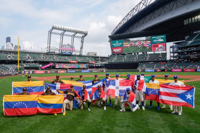 Member of the Padres and Mariners holding up their respective flags from various countries: Venezuela, Colombia, Dominican Republic, Puerto Rico, Mexico, and Cuba. 