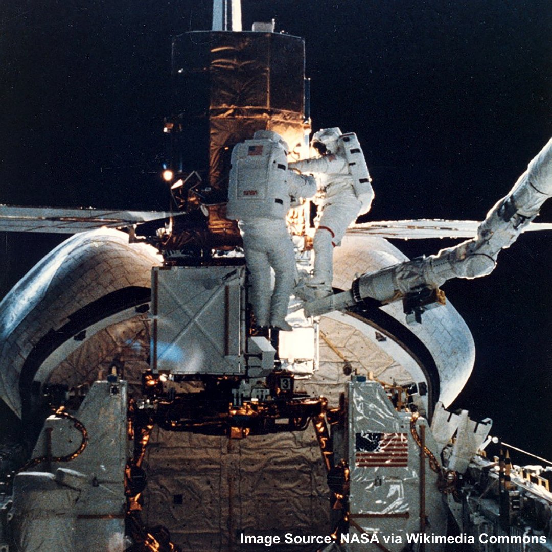 A photograph from the STS-41-C mission. This photo shows astronauts James van Hoften and George Nelson engaged in a spacewalk to repair the Solar Maximum Satellite outside of space shuttle Challenger's open hangar bay.