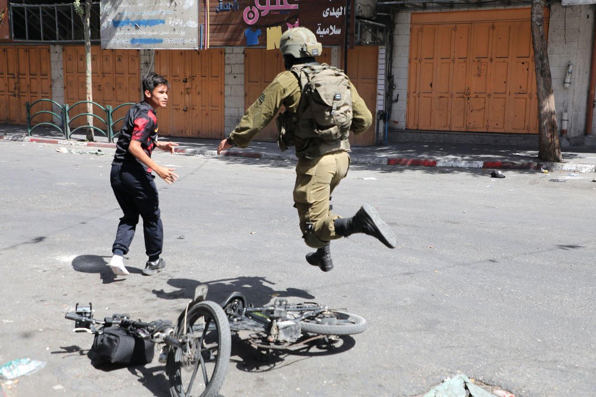 An Israeli soldier chases a Palestinian boy while returning from school in Bab Al-Zawiya area in Hebron, the occupied West Bank. Sep. 29, 2022.