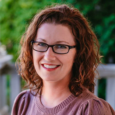 Dr Tiffany LaCroix is a white woman with wavy, shoulder-length brown hair. She is wearing dark-rimmed glasses and a purple sweater.