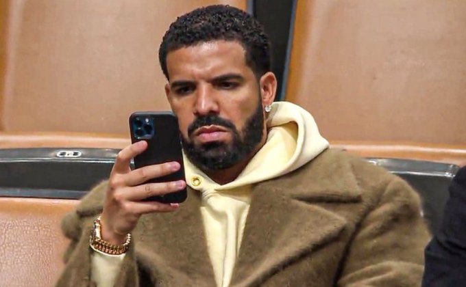 Outtacontextme's tweet photo. What is Drake looking at on his phone? https://t.co/OG8FLXU1AG