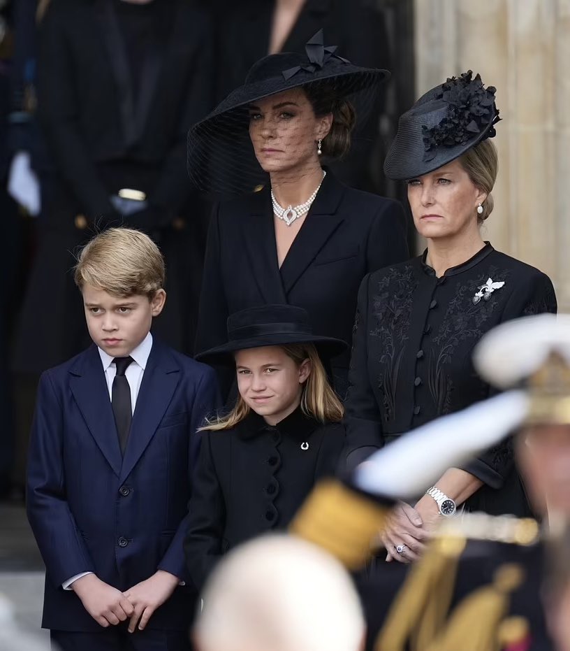 The Princess of Wales and George and Charlotte stand alongside the Countess of Wessex watching the procession set off from the Abbey🖤