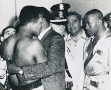 Cassius Clay, soon to be known as Muhammad Ali, is blocked by Sugar Ray Robinson as Heavyweight Champion Sonny Liston stares him down during the chaotic weigh in for their 1964 fight #CassiusClay #MuhammadAli #SugarRayRobinson #SonnyListon #boxing #HeavyweightChampion #1960s #60s