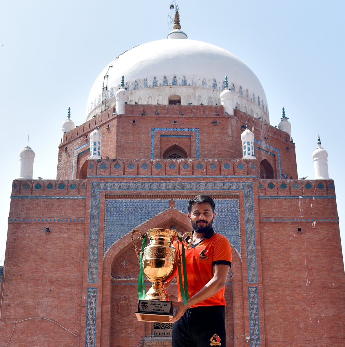Sindh captain <a href="/saudshak/">Saud Shakeel</a> poses with the #NationalT20 trophy with the shrine of Bahauddin Zakariya in the background 🏆

#GharWaliBaat