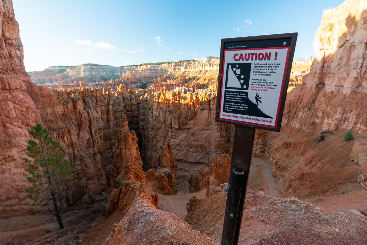 A sign at the top of a red rock canyon reads CAution! Falling rocks are more common on the next 0.5 miles (0.8 km) of trail than any other trail in the park. Rockfalls are unpredictable, can occur at any time, and may result in serious injury or death. Furthermore, loose pebbels on the trails act like marbles beneath your feet. Prevent broken ankles. Wear hiking boots with lug traciton and ankle support. Consider these ricks when hiking this trail.