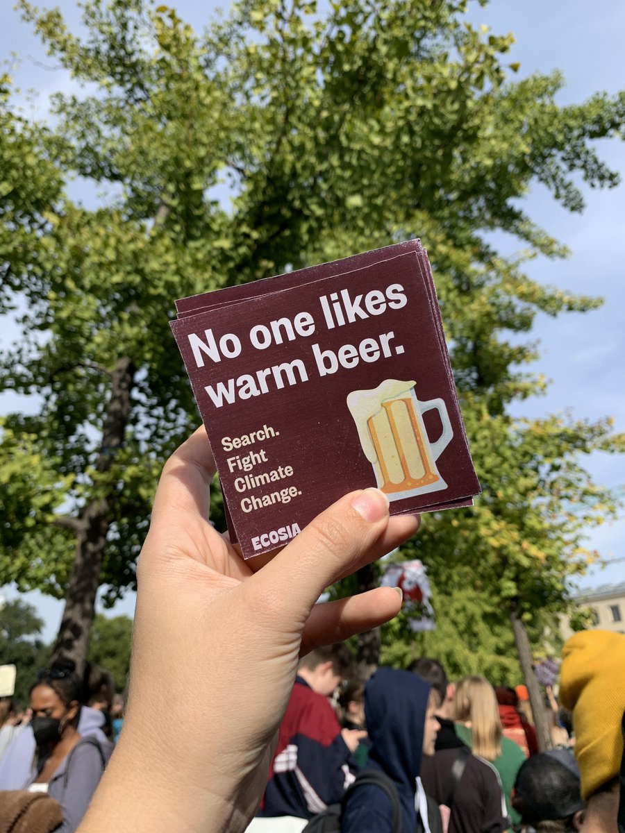 Picture of a hand holding a stack of square stickers that read “No one likes warm beer. Search. Fight climate change.”