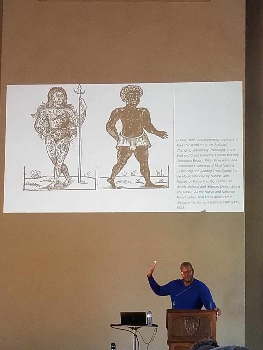 Professor Grier in front of a slide showing two woodcuts, from Bulwer's 1653 Anthropometamorphosis: on the left, a naked woman covered in elaborate tattoos; on the right, a black man. 