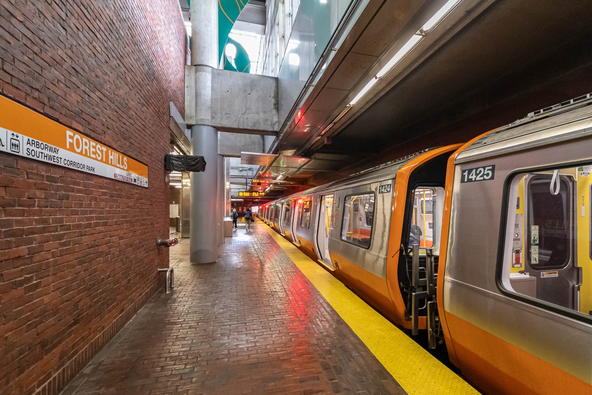 A new Orange Line train stopped with its doors open at Forest Hills station.