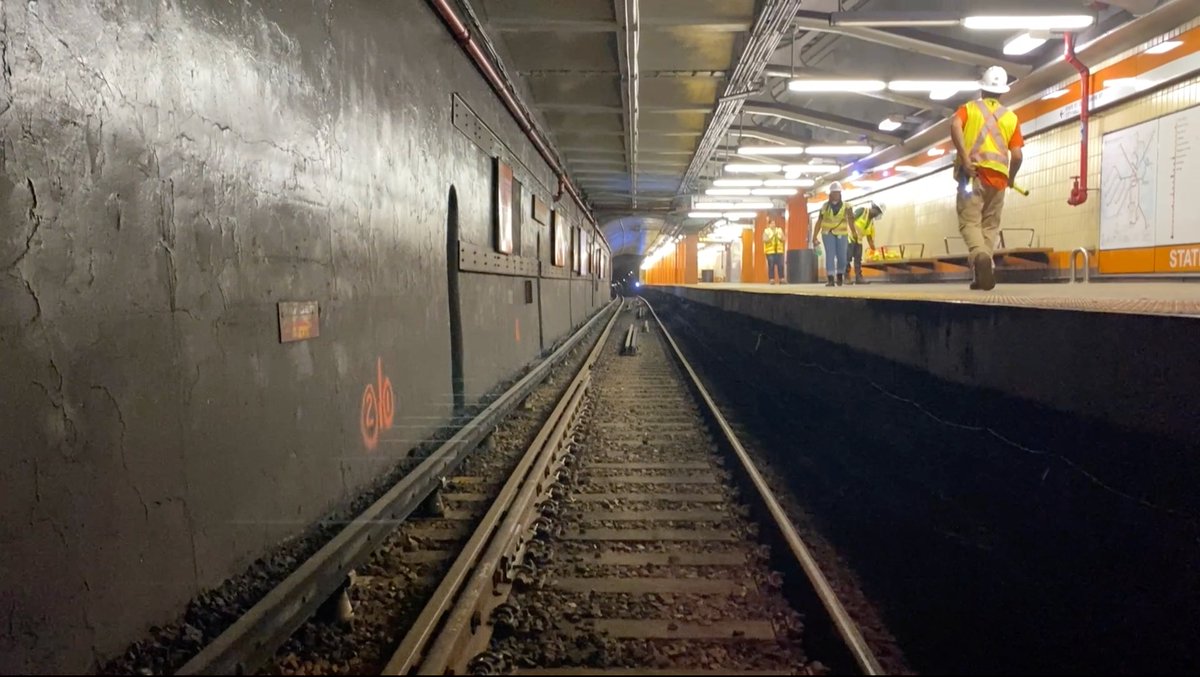 Newly installed rails at State Street station with workers in protective gear on the platform.