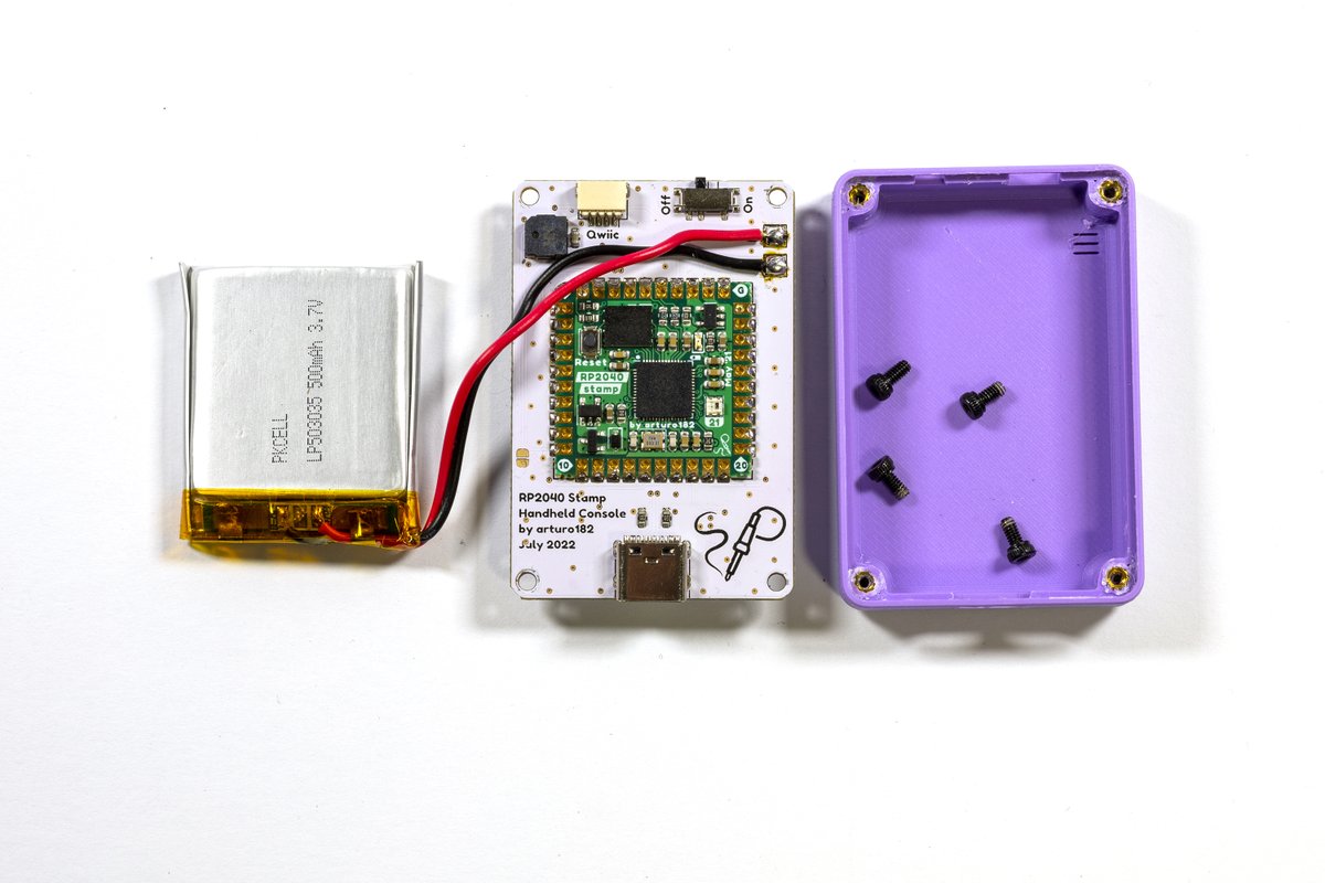 A handheld console back side with battery on on side and a case and screws on the other side. The pcb has a Stamp, type-c connector, speaker, power switch and pads for the battery.