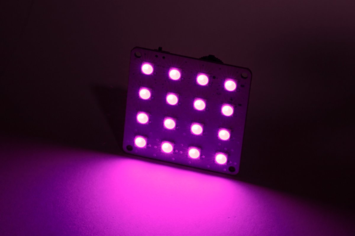 The 4x4 neopixel array on its side shining a fuchsia light all over.